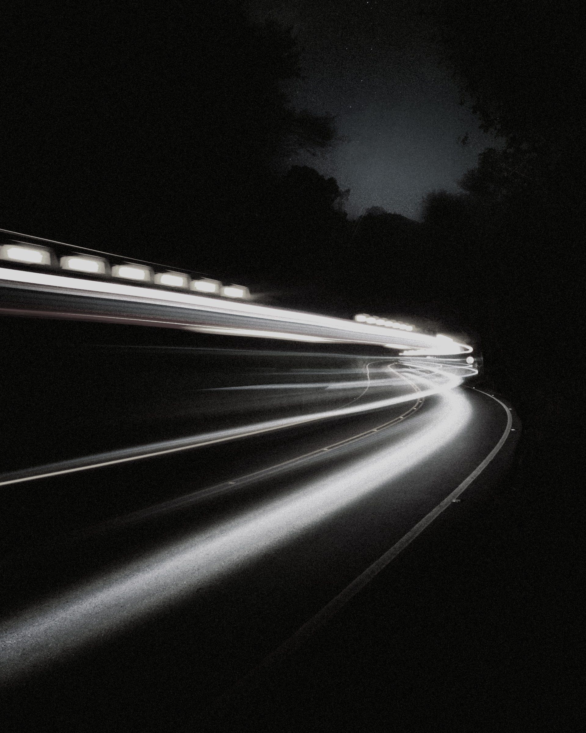 Light trails streaking along a curving road at night