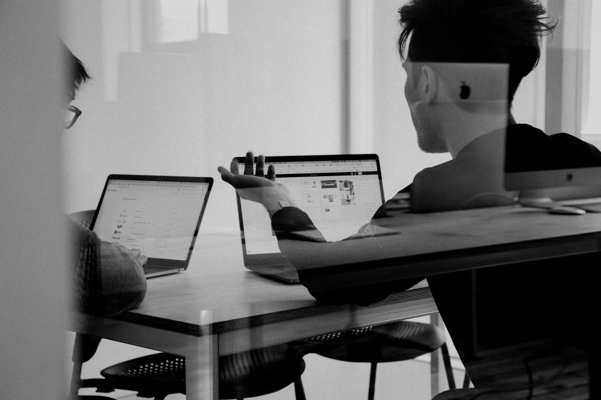 Two colleagues working through a problem together over laptops